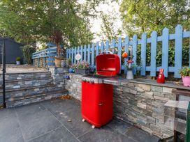 An outdoor area with a red grill and flower pots at Cosy Cottage in Llandegfan near Menai Bridge