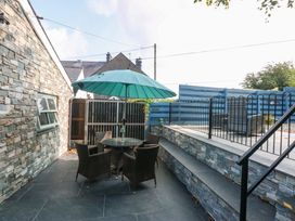 An outdoor area with a table and chairs under an umbrella at Cosy Cottage in Llandegfan near Menai Bridge