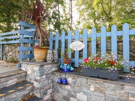 An outdoor garden area with a blue picket fence and flower pots at Cosy Cottage in Llandegfan near Menai Bridge