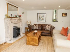 A living room with a brown leather sofa, beige sofa, wooden coffee table, decorative fireplace, and floral artwork at Garden Cottage in Garndolbenmaen near Tremadog