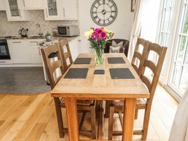A wooden dining table with four chairs and a vase of flowers in a kitchen with cabinets and appliances at Garden Cottage in Garndolbenmaen near Tremadog