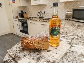 A kitchen with granite countertops with a bottle of Welsh cider and wrapped bread labeled Bara Brith at Garden Cottage in Garndolbenmaen near Tremadog
