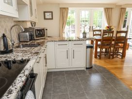 A kitchen with a marble countertop dining table and wooden chairs near glass doors at Garden Cottage in Garndolbenmaen near Tremadog