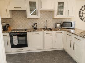 A kitchen with white cabinets a countertop oven kettle toaster microwave and sink at Garden Cottage in Garndolbenmaen near Tremadog