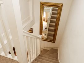 A staircase with carpeted steps and a large gold-framed mirror on the wall at Garden Cottage in Garndolbenmaen near Tremadog