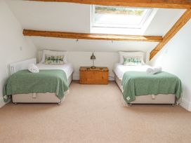 A bedroom with two single beds green blankets a wooden chest and a skylight window at Garden Cottage in Garndolbenmaen near Tremadog