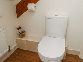 A bathroom with a white toilet a roll of toilet paper on the wall and a small plant in a wicker basket at Garden Cottage in Garndolbenmaen near Tremadog