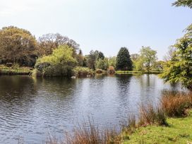 A pond surrounded by trees and grass at Garden Cottage in Garndolbenmaen near Tremadog