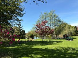 A garden with a pond trees and picnic tables at Garden Cottage in Garndolbenmaen near Tremadog