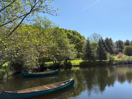 A pond with two canoes and trees surrounding the water at Garden Cottage in Garndolbenmaen near Tremadog