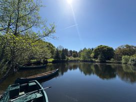A small lake with three boats and trees on the shore at Garden Cottage in Garndolbenmaen near Tremadog