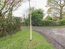 A road sign on a grassy area near a fork in a rural road with trees and bushes around at Shepherds Hut in Colton near Rugeley Staffordshire