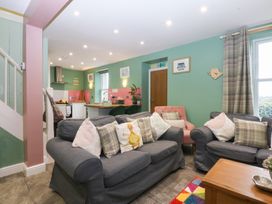 A living room with sofas and a kitchen area at Tregynrig Bach in Cemaes Bay