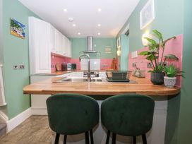 A kitchen with an island and bar stools at Tregynrig Bach in Cemaes Bay