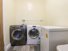 A utility room with washing machine dryer and freezer at Tregynrig Bach in Cemaes Bay