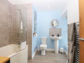 A bathroom with a shower, bathtub, toilet, and sink at Tregynrig Bach in Cemaes Bay