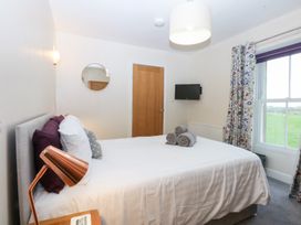 A bedroom with a bed, towels, and a television at Tregynrig Bach Cemaes Bay