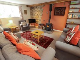 A living room with a sofa and a stove at One Town End in Mungrisdale, Mosedale