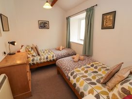 A bedroom with twin beds and a lamp at One Town End, Mungrisdale, Mosedale