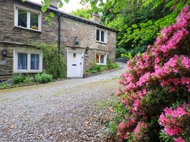 A stone cottage with a gravel pathway and flowers at Fellside Cottage in Bowness-On-Windermere