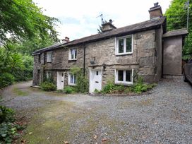 A stone cottage with a gravel driveway at Fellside Cottage in Bowness-On-Windermere
