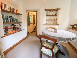 A dining room with bookshelves and a table at Fellside Cottage in Bowness-On-Windermere