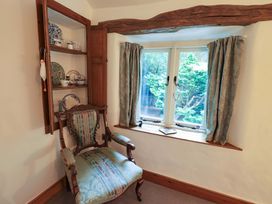 A snug area with a chair, shelf, and window at Fellside Cottage, Bowness-On-Windermere