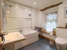 A bathroom with a bathtub and shower along with a toilet and sink at Fellside Cottage in Bowness-On-Windermere