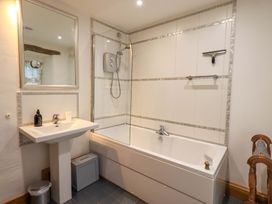 A bathroom with a bathtub, shower, sink and mirror at Fellside Cottage in Bowness-On-Windermere