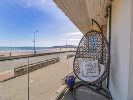 A balcony with a hanging chair and flowers at Ocean View Apartment in Colwyn Bay