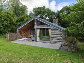 A cabin with a deck and stone chimney at The Hare's Shack in Garnett Bridge, Longsleddale. Near Kendal