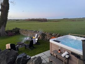 An outdoor area with a hot tub and fire pit at Dolwaenydd in Brynsiencyn