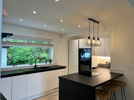 A kitchen with black countertops white cabinets an island with stools and hanging lights at Afallon in Menai Bridge