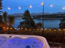 An outdoor hot tub overlooking a river with decorative lights at Afallon in Menai Bridge