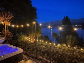 An outdoor area with a hot tub and string lights overlooking water and mountains at Afallon in Menai Bridge