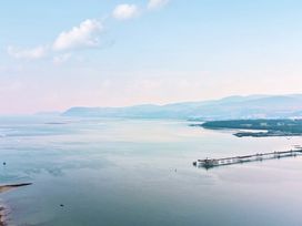 An aerial view of a pier over calm water with mountains in the background at Afallon in Menai Bridge