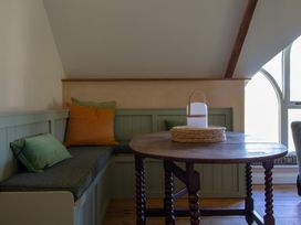 A dining area with a round table and cushions at Carrows Stable in Morwenstow