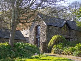 A stone house with windows and grass in front at Carrows Stable in Morwenstow