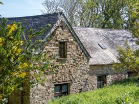 A stone building with a sloped roof and windows at Carrows Stable in Morwenstow