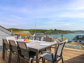 An outdoor dining area with a table and chairs overlooking the water at The Penthouse in Salcombe