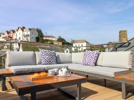 An outdoor sofa with pillows and a table set with a teapot and croissants at The Penthouse in Salcombe