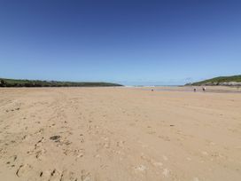 A beach with sand and people walking at No 1 The Hinges Crantock