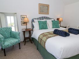 A bedroom with a bed and a chair at Dolwylan Cottage in Cwmtydu near New Quay
