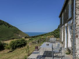 An outdoor area with a table and benches overlooking the sea at Dolwylan Cottage Cwmtydu near New Quay