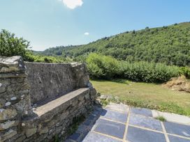 An outdoor area with a stone bench and views of hills at Dolwylan Cottage Cwmtydu near New Quay