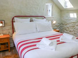 A bedroom with a bed and bedside table at Dolwylan Barn Cwmtydu near New Quay