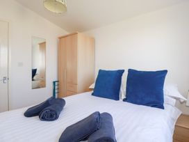 A bedroom with a bed with blue pillows and towels a wooden wardrobe and a wall mirror at 224 Atlantic Bays in St Merryn