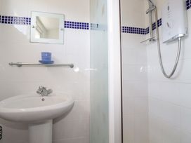A bathroom with a white sink a mirror a towel rack with a blue cup and saucer and a shower with a hose and control at 224 Atlantic Bays in St Merryn