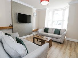 A living room with two sofas a wall mounted television and a wooden coffee table at Apartment 1 - Llandudno Central in Llandudno