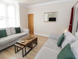 A living room with two grey sofas green cushions wooden coffee tables a wooden door and a wall mirror at Apartment 1 - Llandudno Central in Llandudno